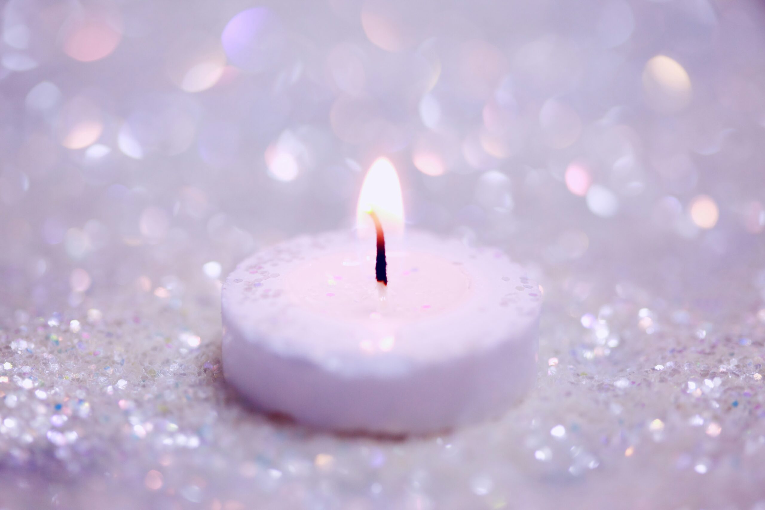 Picture of a lilac candle on a lilac glittery soft focus background