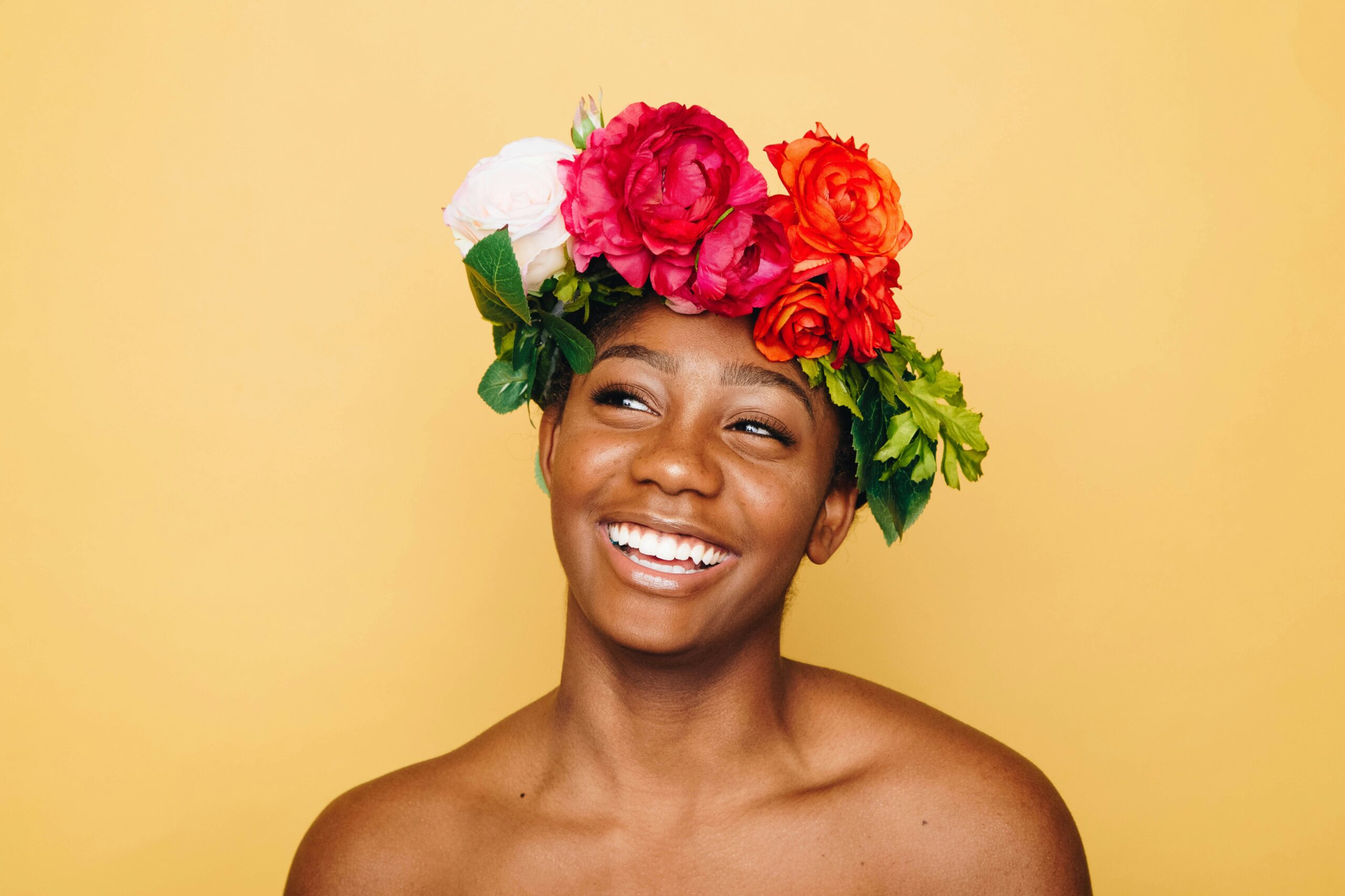 Photo of confident joyful woman wearing bright flowers in her hair.