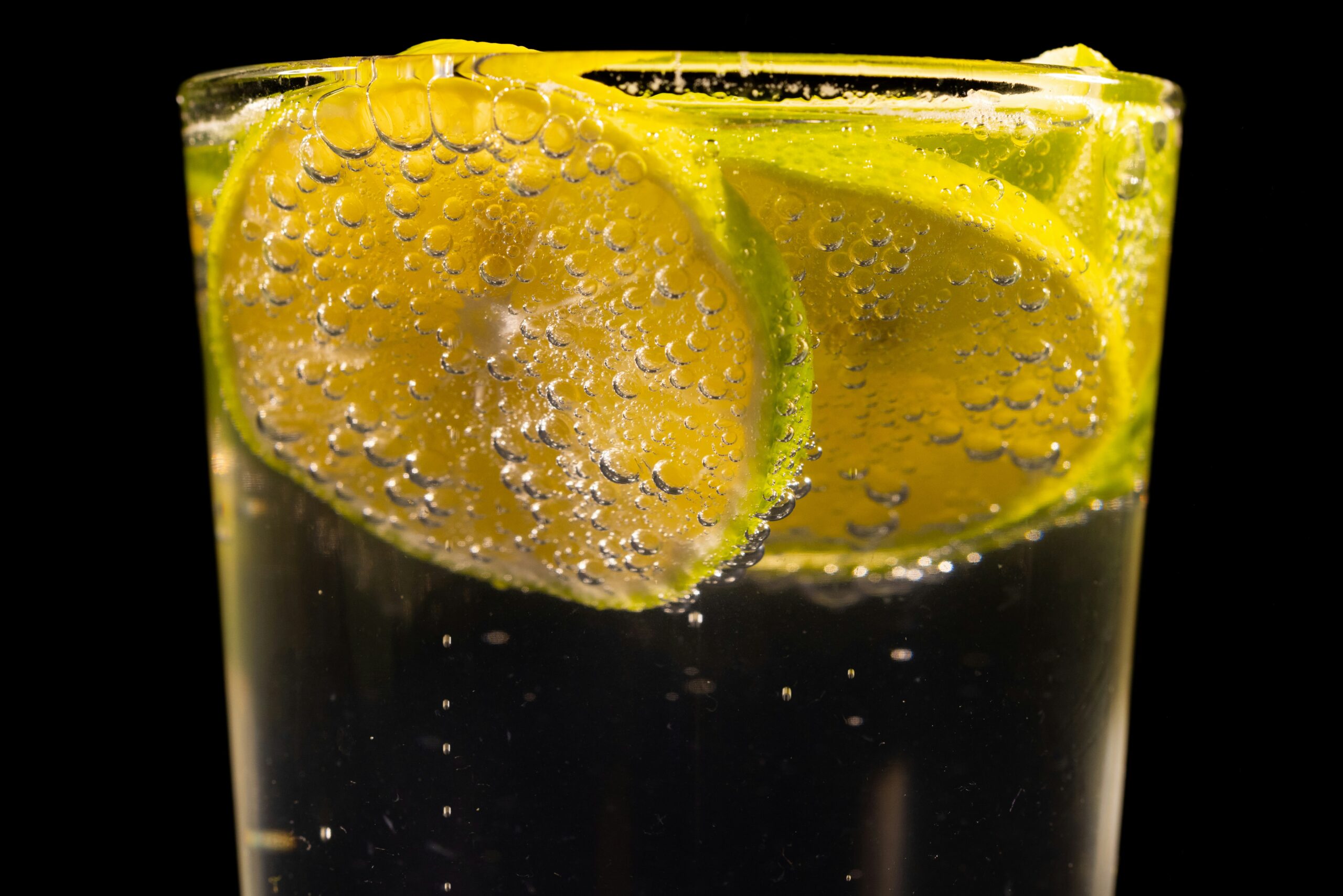 Photo of a cool drink in a glass with lemon and lime slices and a few bubbles.