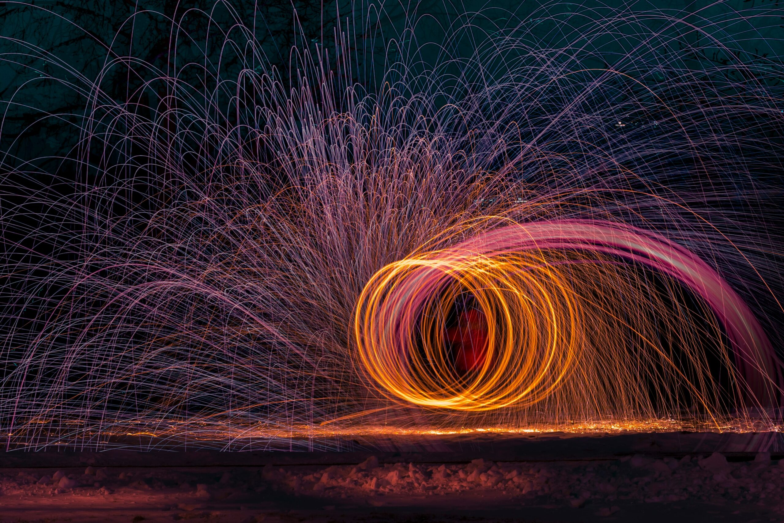 Photo of a very large orange and pink Catherine Wheel firework with sparks in a night sky