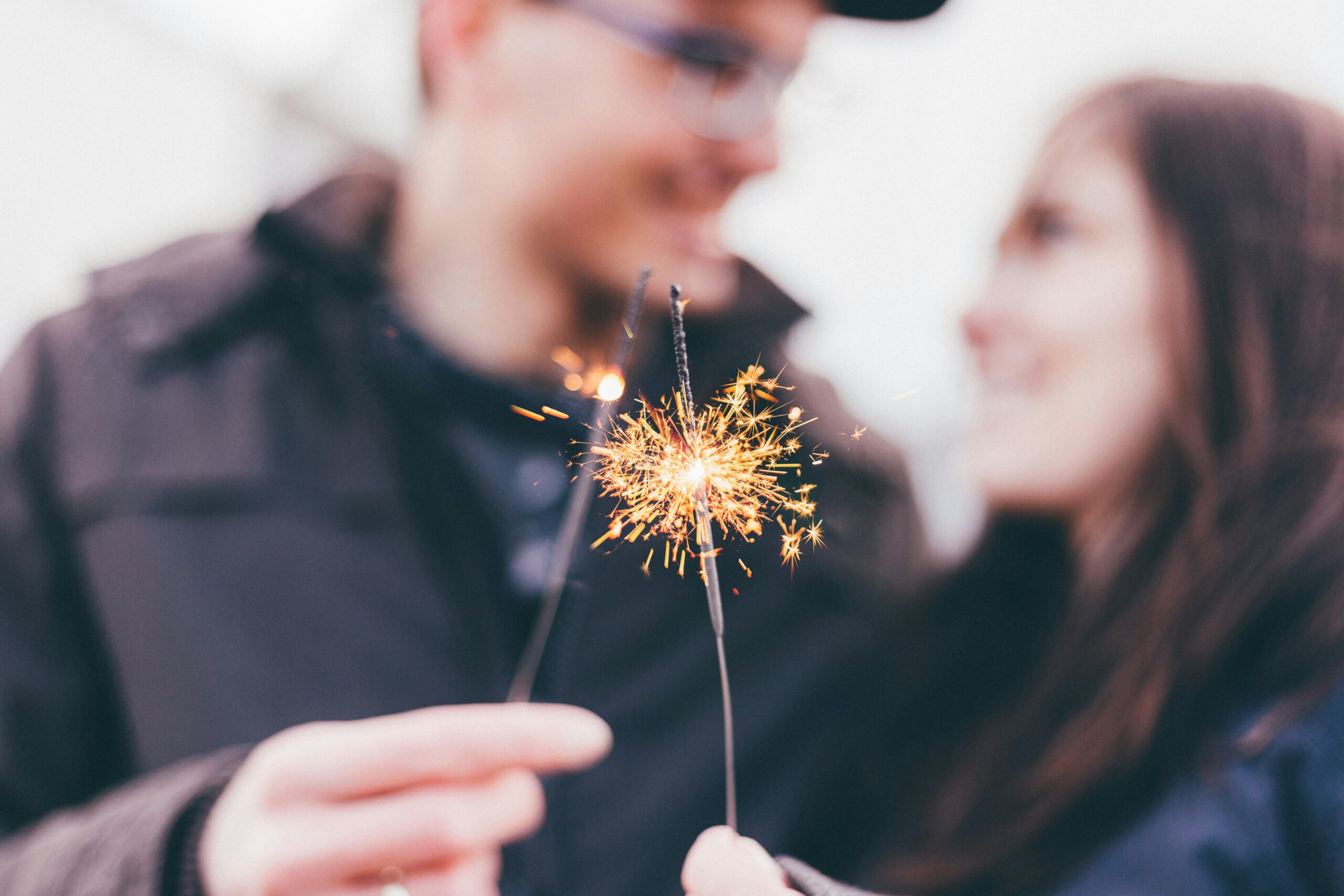 Couple holding sparklers close together at night, symbolising reignited intimacy and connection.